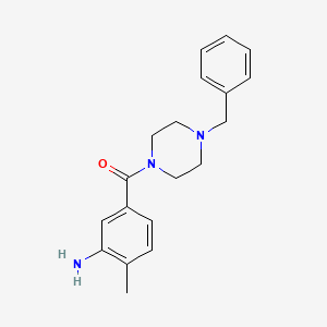 molecular formula C19H23N3O B1451700 5-[(4-Benzylpiperazin-1-yl)carbonyl]-2-methylaniline CAS No. 1018563-38-6