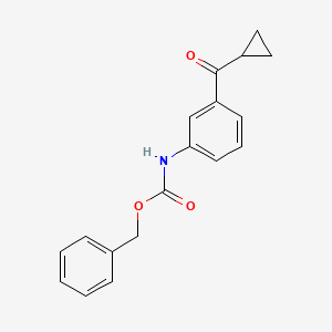 molecular formula C18H17NO3 B1611456 (3-Cyclopropanecarbonyl-phenyl)-carbamic acid benzyl ester CAS No. 162174-76-7